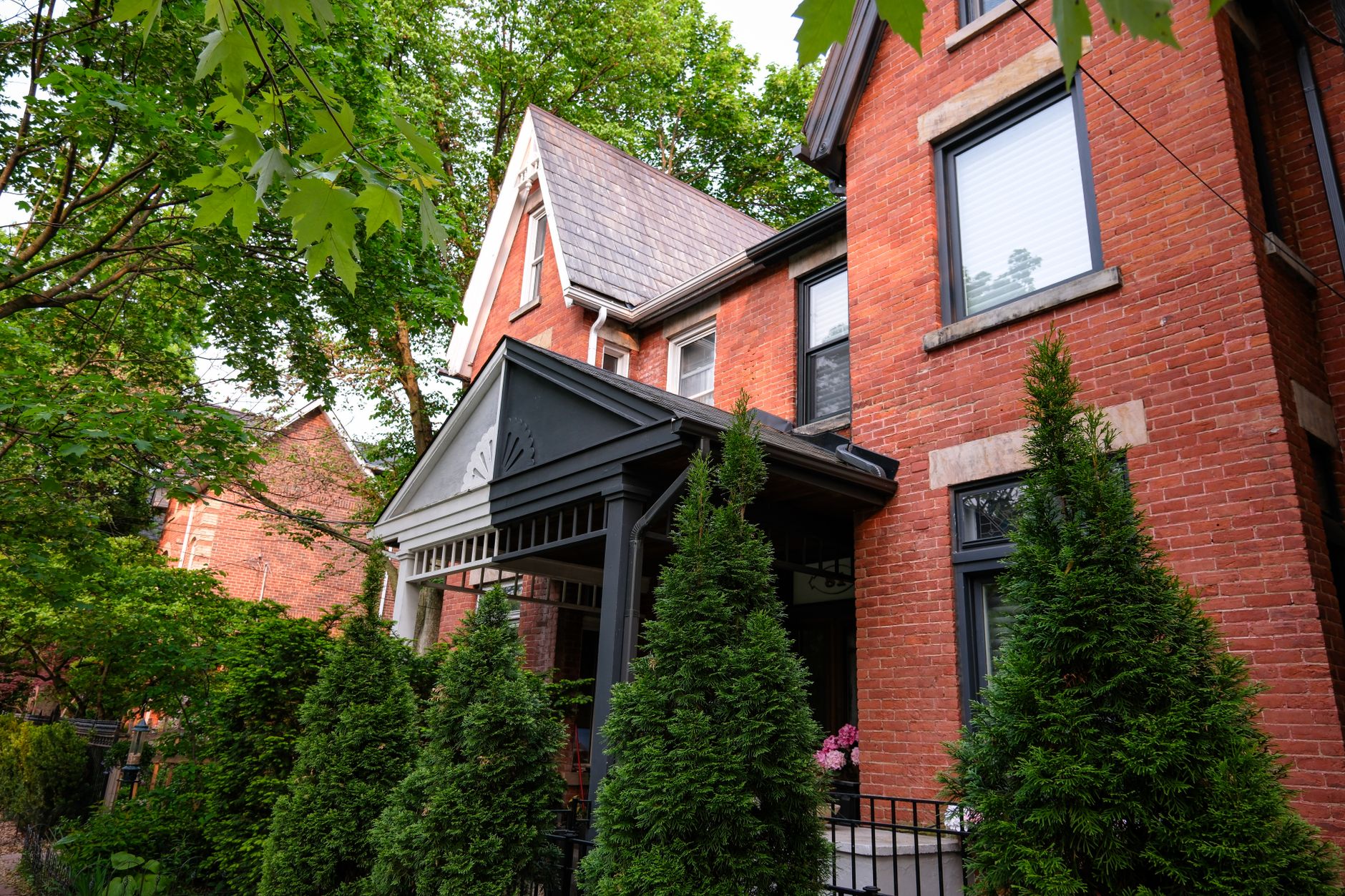 Red brick house with lush greenery in a Toronto neighbourhood
