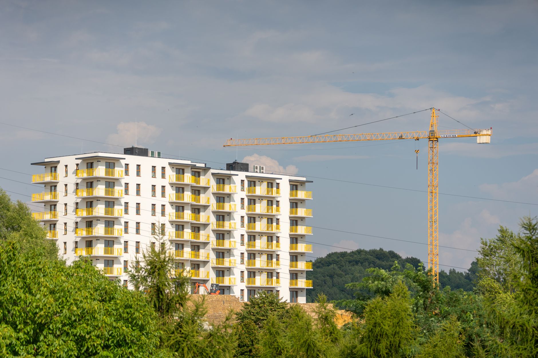 An apartment building under construction, with a tower crane standing beside it.