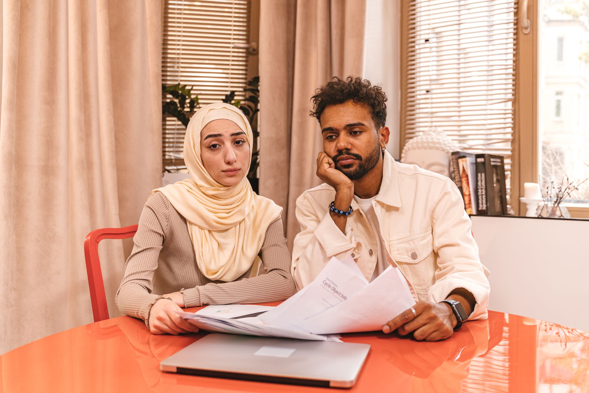 A couple sitting at a table reviewing property paperwork with a laptop open beside them