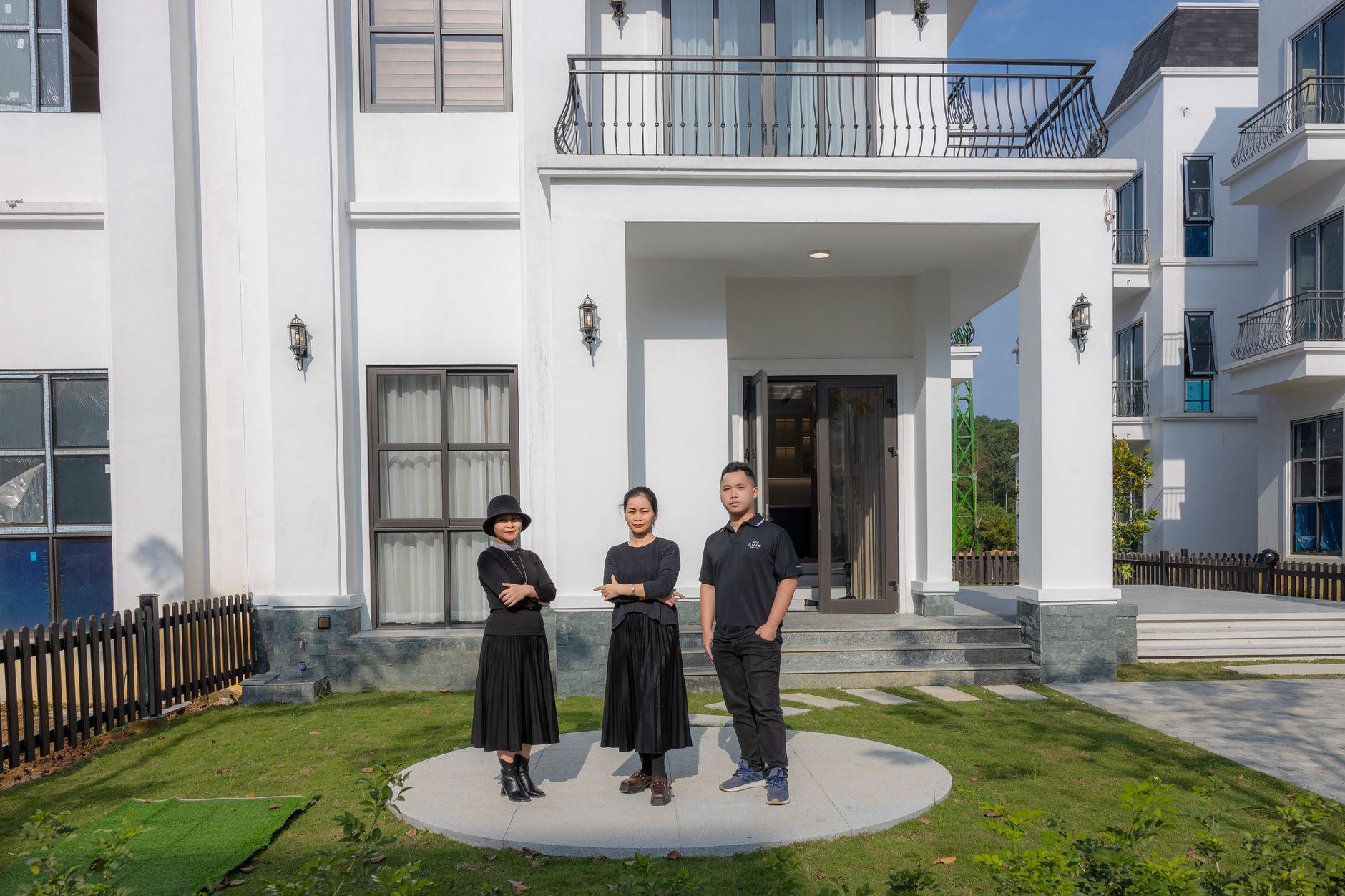 A family standing outside a newly built house on a bright day.