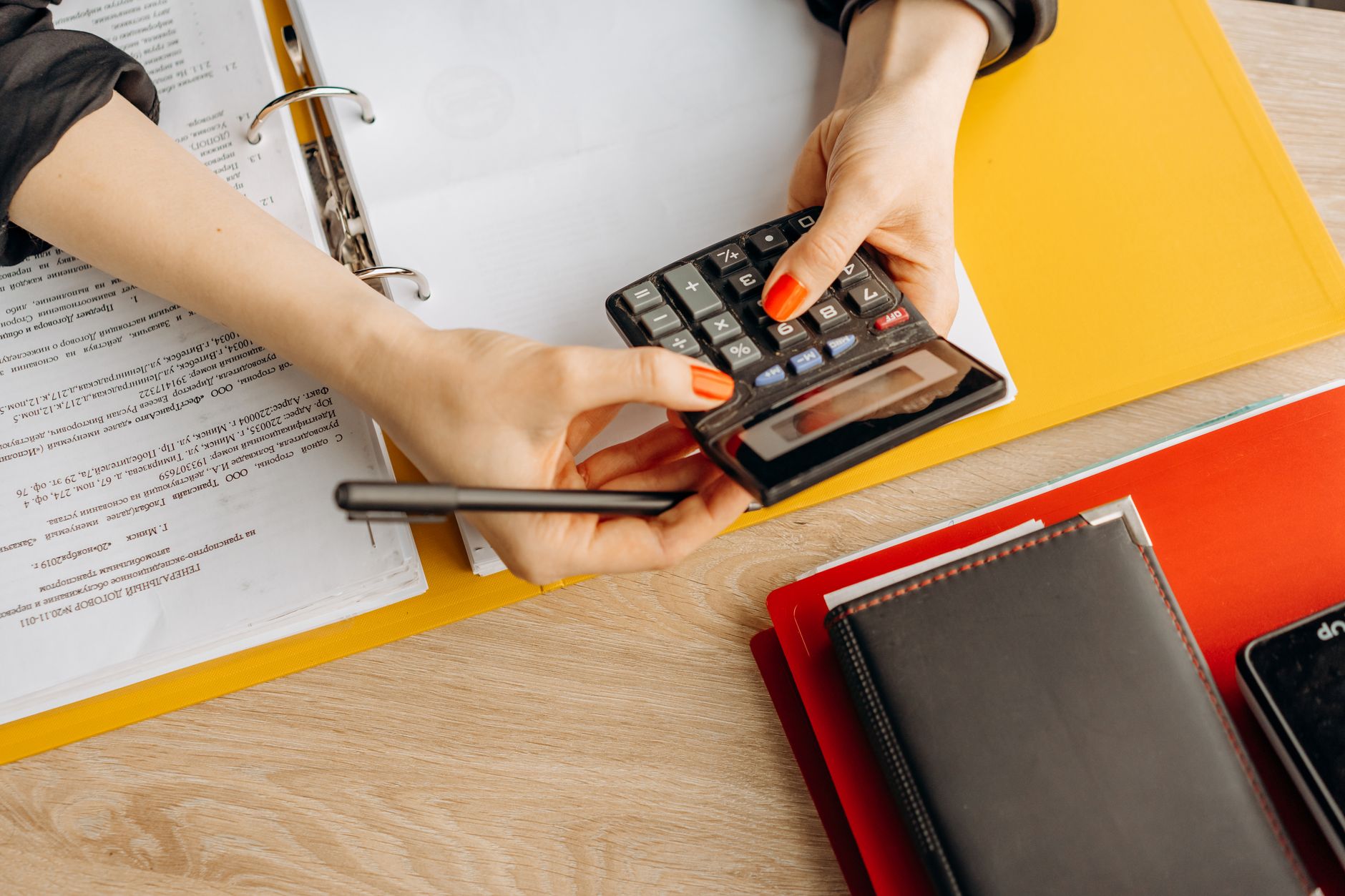 Hands working through paperwork with a calculator at a desk