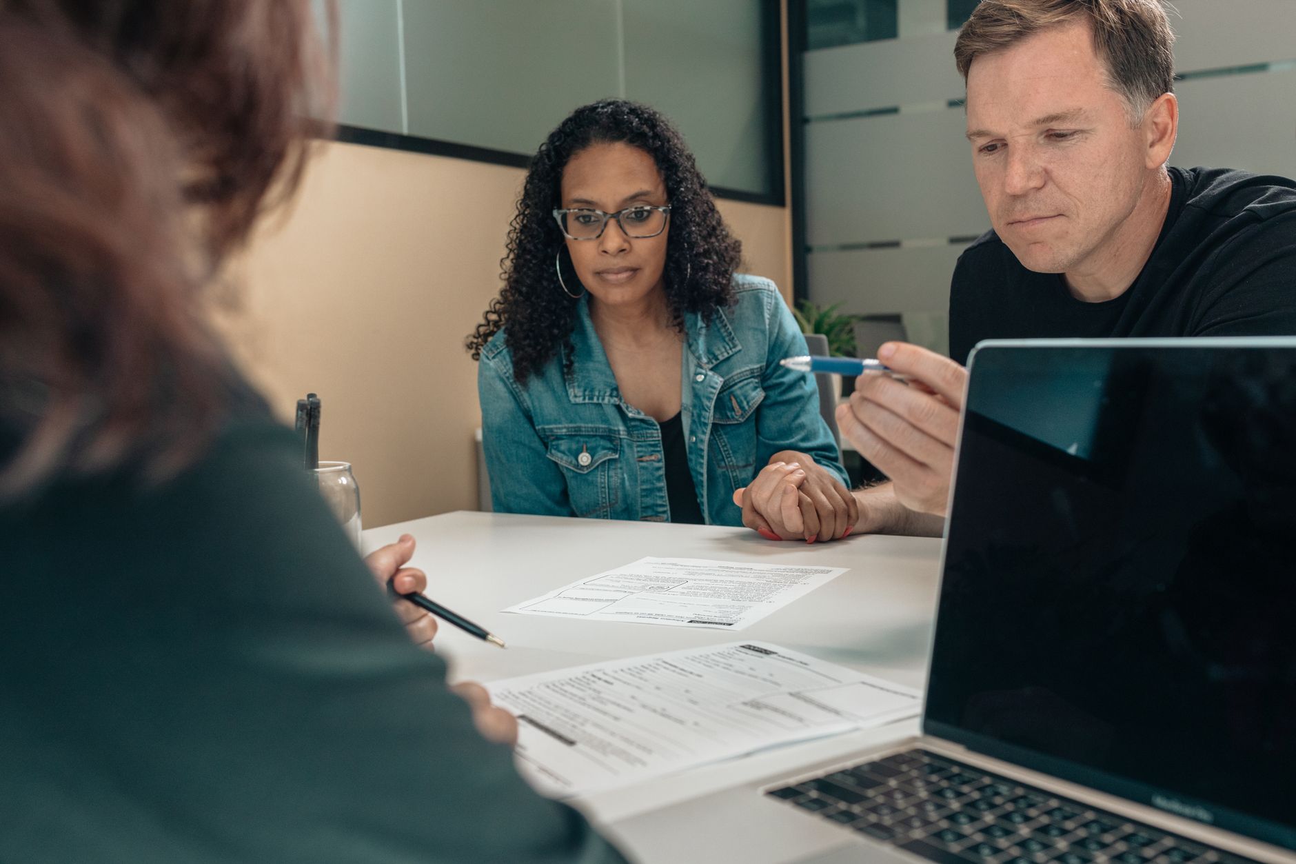 A couple at a table while someone goes through the paperwork in front of them.